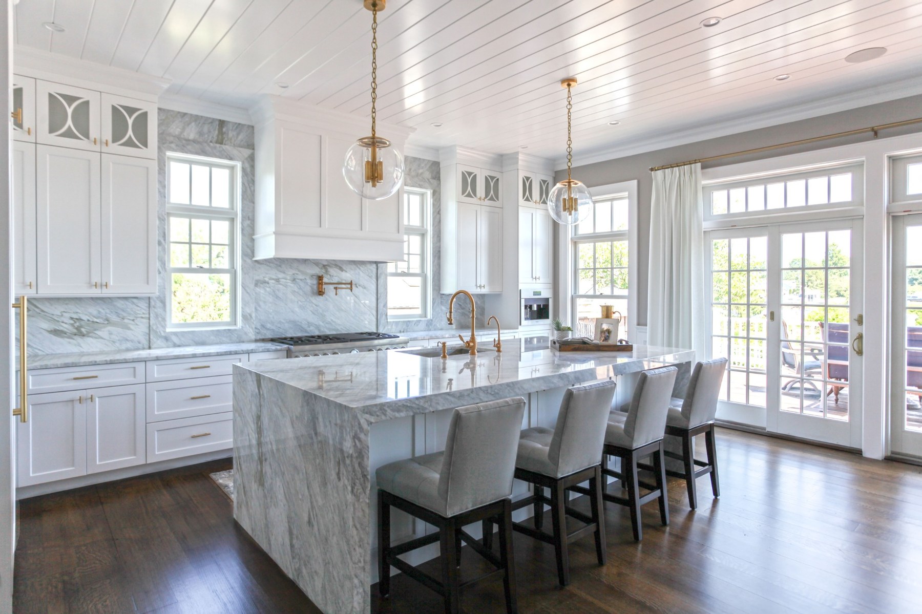 Bright white kitchen with a large marble island and warm natural light.