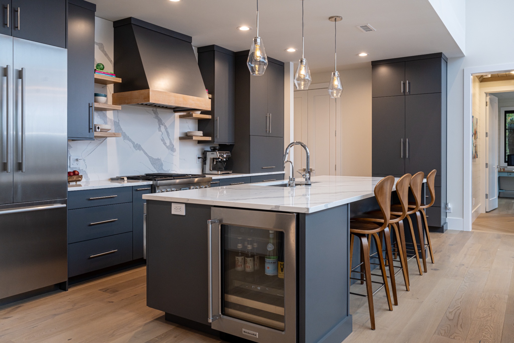 Refined dark kitchen with island seating and layered shelving.